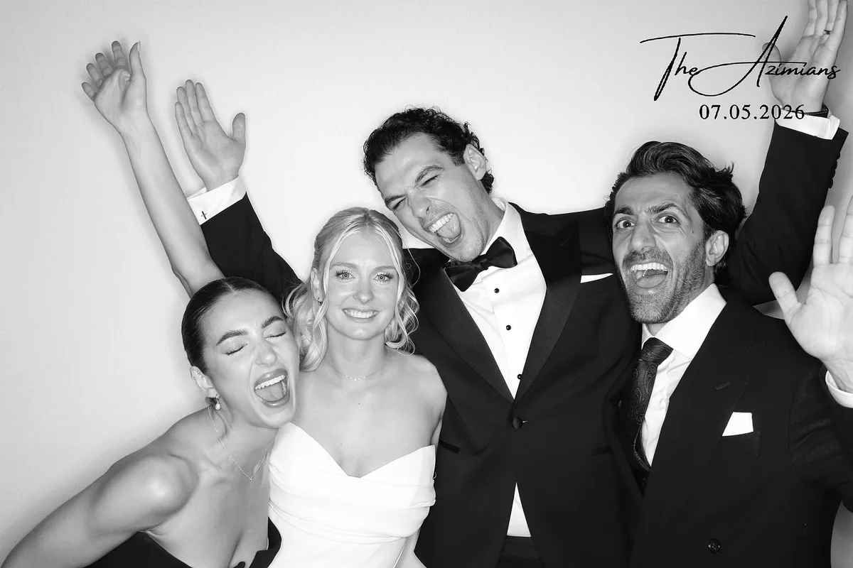 Bride and wedding party celebrating in a glam photo booth, black-and-white finish: glam photo booth rental in Burlington