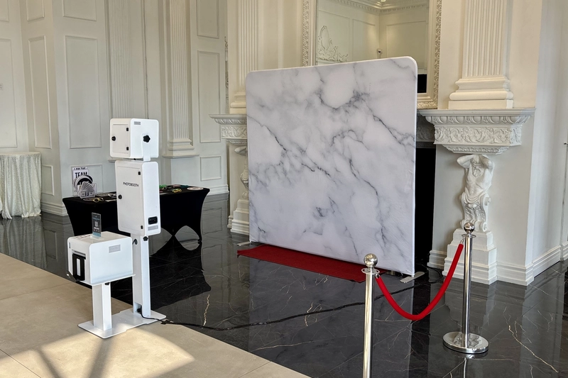 Instant photo booth set up in a banquet hall with a white marble backdrop, red carpet and stanchions: instant photo booth rental in Hamilton