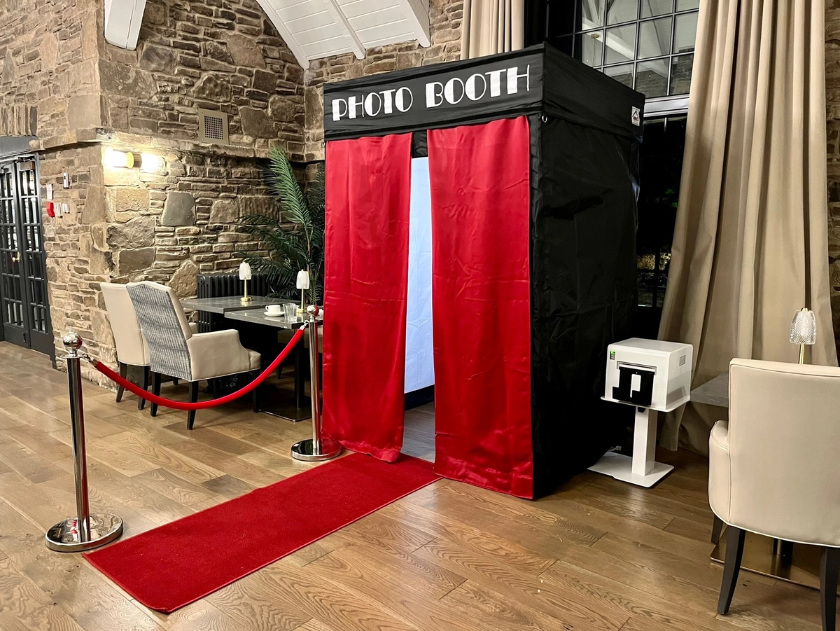 Red-curtained private photo booth on a red carpet in a stone-walled dining room: private photo booth rental in Hamilton