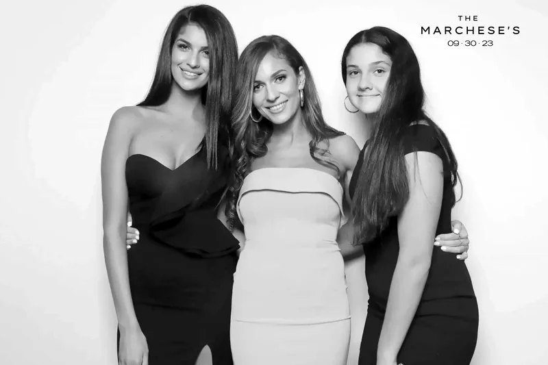 Three guests in evening dresses in a black-and-white glam photo booth shot with a custom event overlay: photo booth rental in Mississauga
