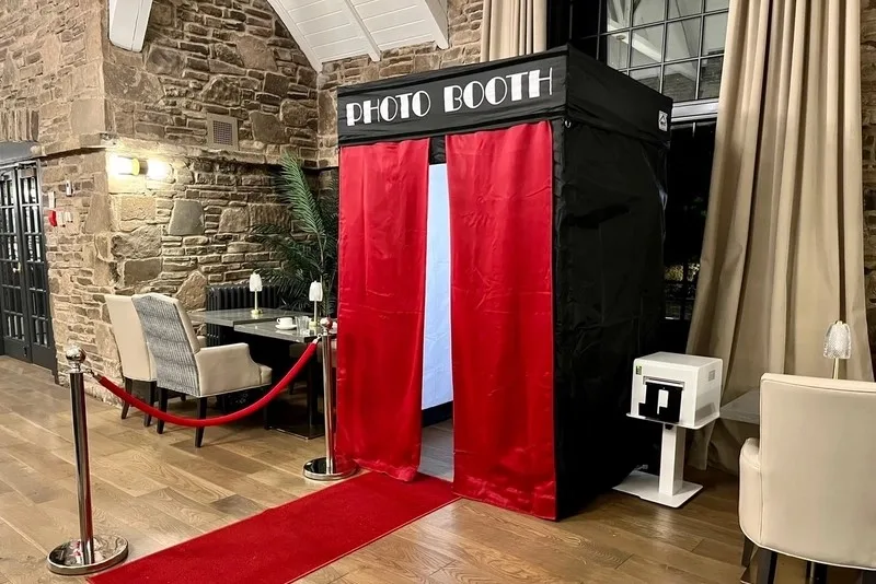 Private photo booth with red curtains, stanchions and a print station in a stone-walled room: private photo booth rental in Mississauga