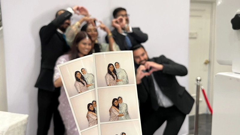 Group posing for an instant photobooth with a image print offs held up